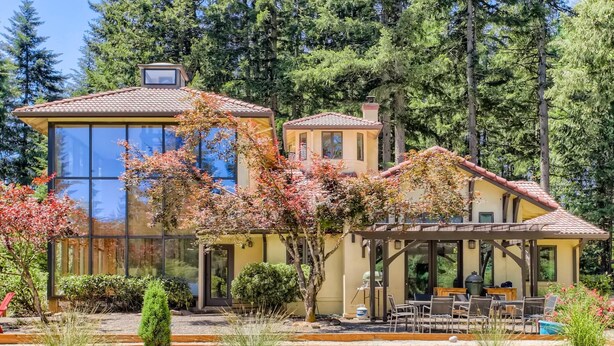 Una casa de dos pisos con un patio y una pérgola.