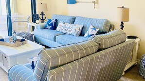 A living room with a blue-striped sofa, a small white table, and a lamp.