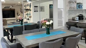 A modern kitchen with a dining area, featuring a large table, grey chairs, and a ceiling fan. - 3BR 10 Guest with Pvt. Jacuzzi 2 pools Gated Comm. AC Security 24-7 (Rosarito)