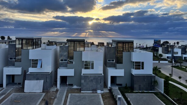 A modern residential complex with multiple buildings, a clear view of the sea, and a sunset in the background. - 3BR 10 Guest with Pvt. Jacuzzi 2 pools Gated Comm. AC Security 24-7 (Rosarito)