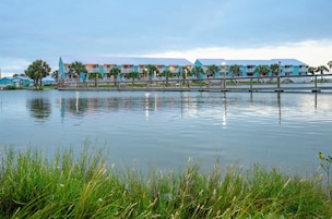 A waterfront hotel with multiple balconies, a dock, and a calm lake.