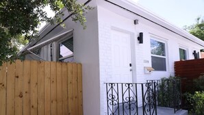 Einbungalow mit weißer Fassade, Holzzaun und schwarzem schmiedeeisernen Geländer.