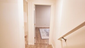 Un escalier menant à une pièce dotée d’un plancher en bois et d’un tapis à motifs.