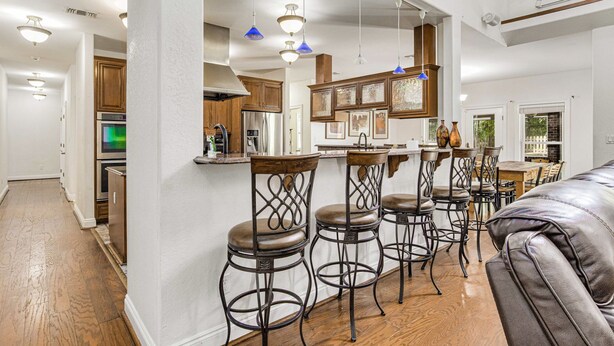 Una cucina moderna con mobili in legno, un'isola centrale e sgabelli da bar.