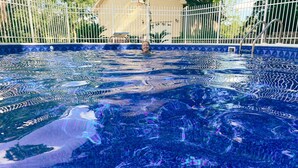 Una piscina con un motivo a mosaico geometrico e una recinzione in metallo.