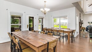 Un'ampia sala da pranzo con un lungo tavolo in legno e numerose sedie, ampie finestre e un lampadario.