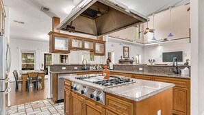 Un'ampia cucina con isola centrale, mobili in legno e piano cottura in acciaio inossidabile.