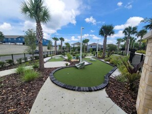A well-maintained courtyard with artificial grass, palm trees, and a circular walking path. - Paradise Resort (Davenport)