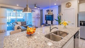 A modern kitchen with granite countertops, stainless steel appliances, and pendant lighting. - Paradise Resort (Davenport)
