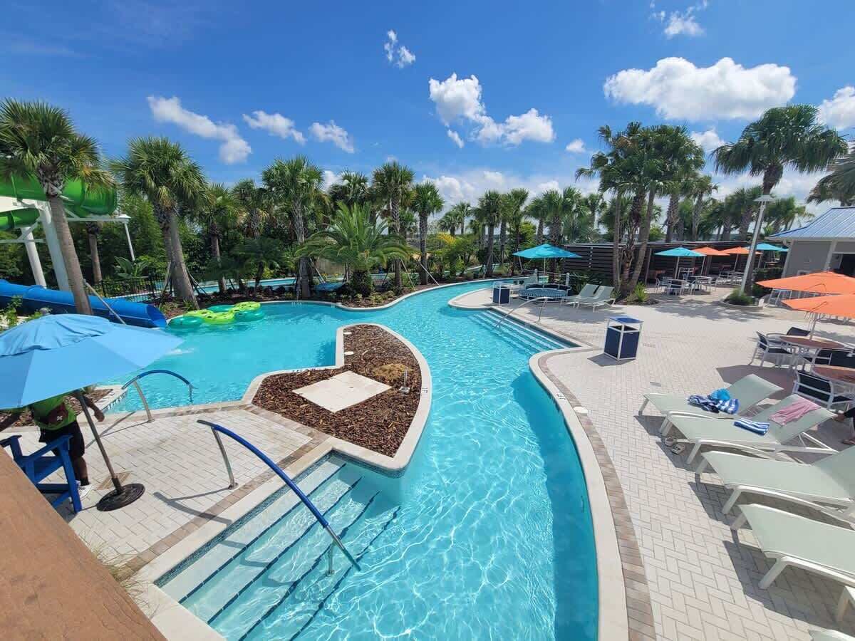 A pool area with a water slide, lounge chairs, and umbrellas.