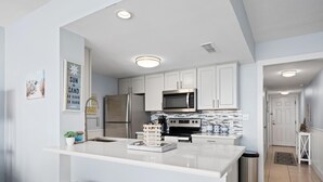 Una cocina moderna con armarios blancos, electrodomésticos de acero inoxidable y una isla central con taburetes.
