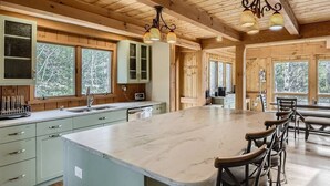 Une cuisine spacieuse dotée d’un grand îlot central, de meubles en bois et offrant une vue sur l’extérieur.