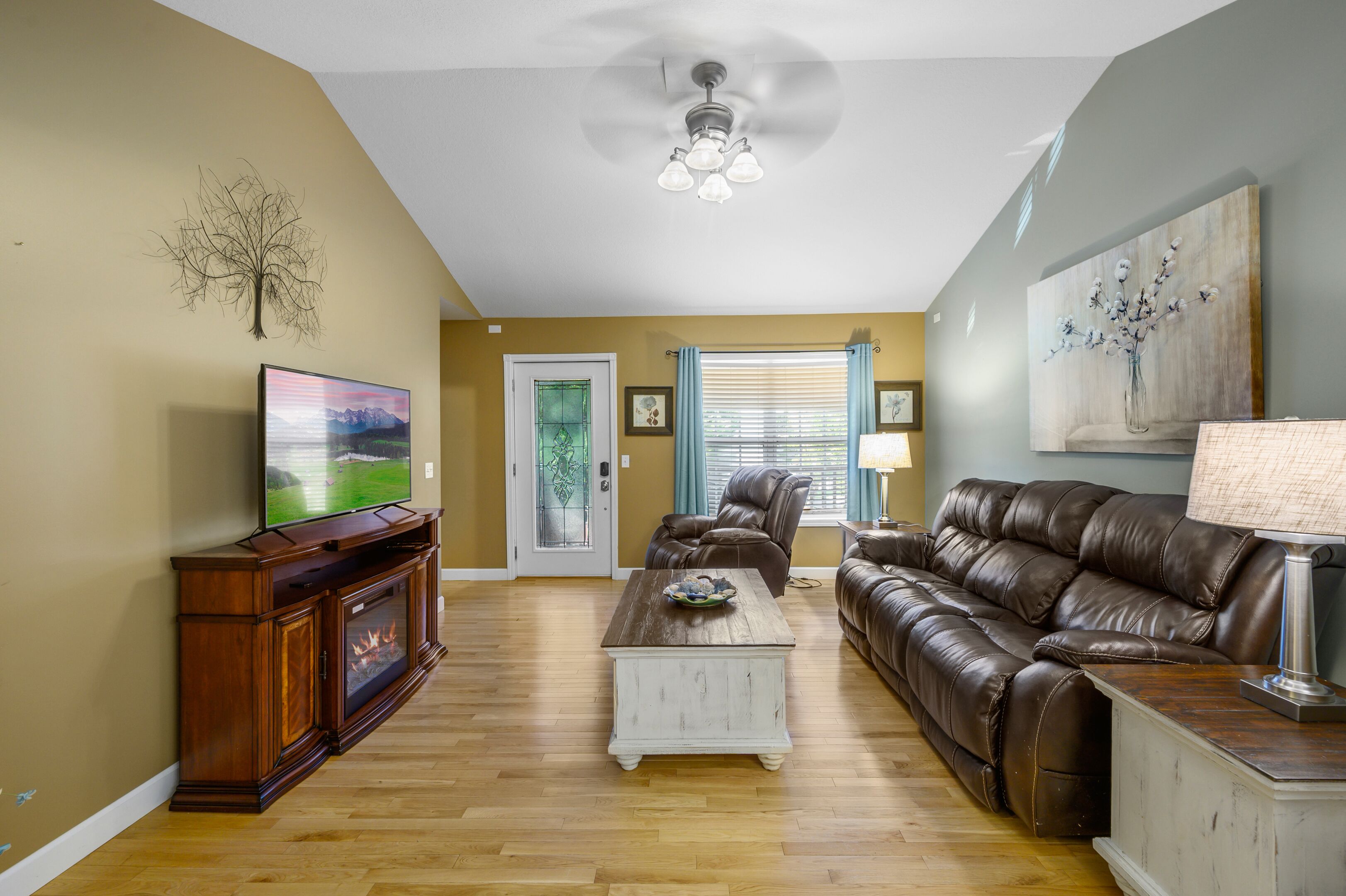 Una sala de estar con chimenea, sofá de cuero y televisor.