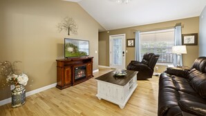 A living room with a fireplace, leather sofa, and a television.