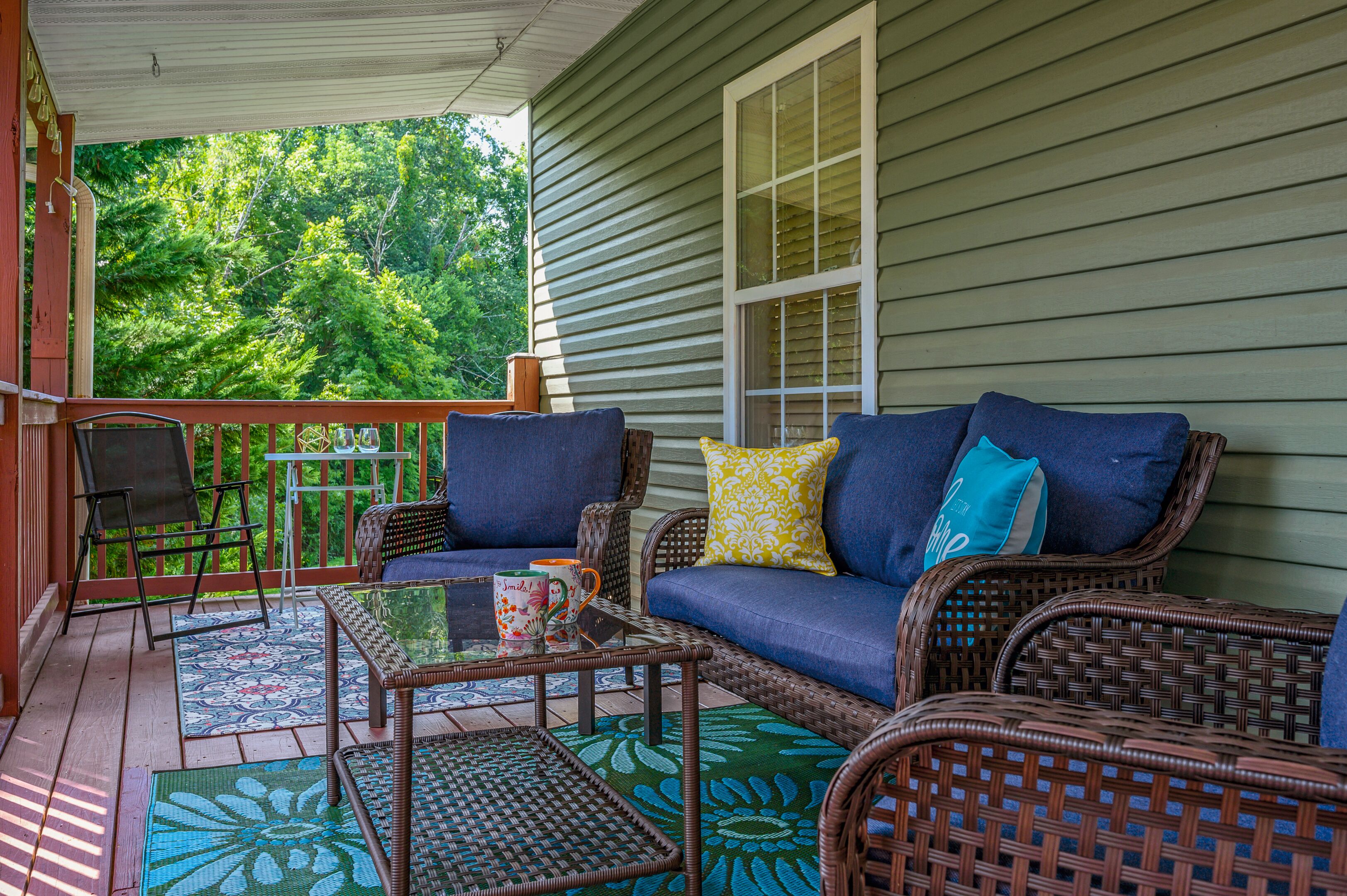 A covered porch with wicker furniture, a small table, and a chair.