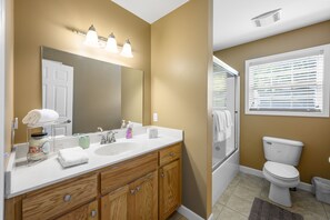 Une salle de bain avec un lavabo blanc, un meuble-lavabo en bois et des toilettes.