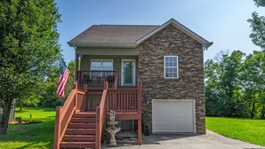 A two-story house with a stone exterior, a front porch, a flag, and a garage.