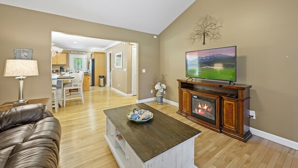 A living room with a fireplace, a television, and a dining area in the background.