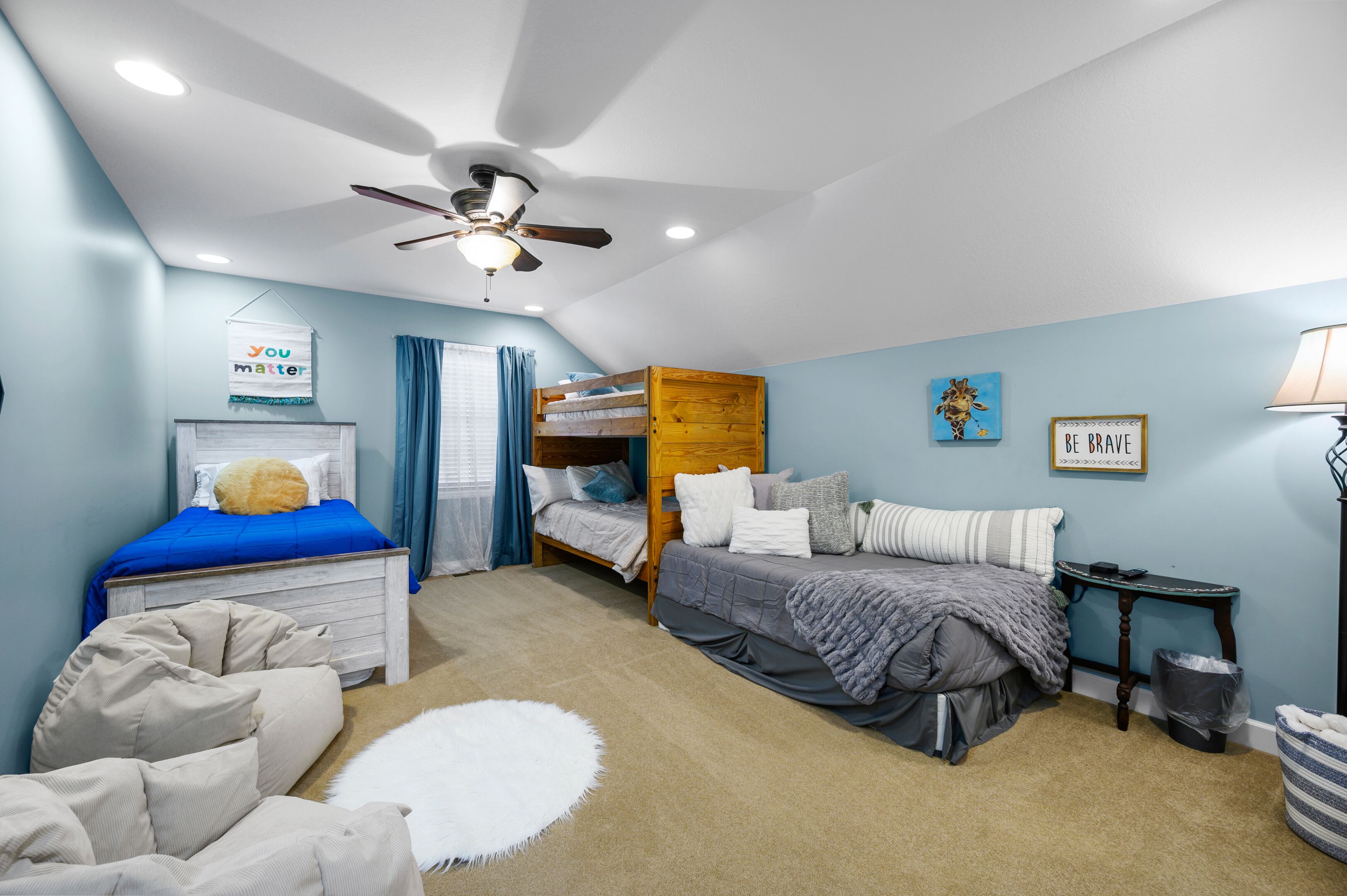 A bedroom with bunk beds, a ceiling fan, a whiteboard, and a motivational poster.
