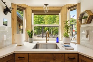 A kitchen with a large window, wooden cabinets, and a stainless steel sink.