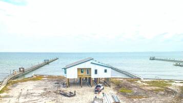 A coastal building with a pier extending into the sea, surrounded by construction materials and equipment.