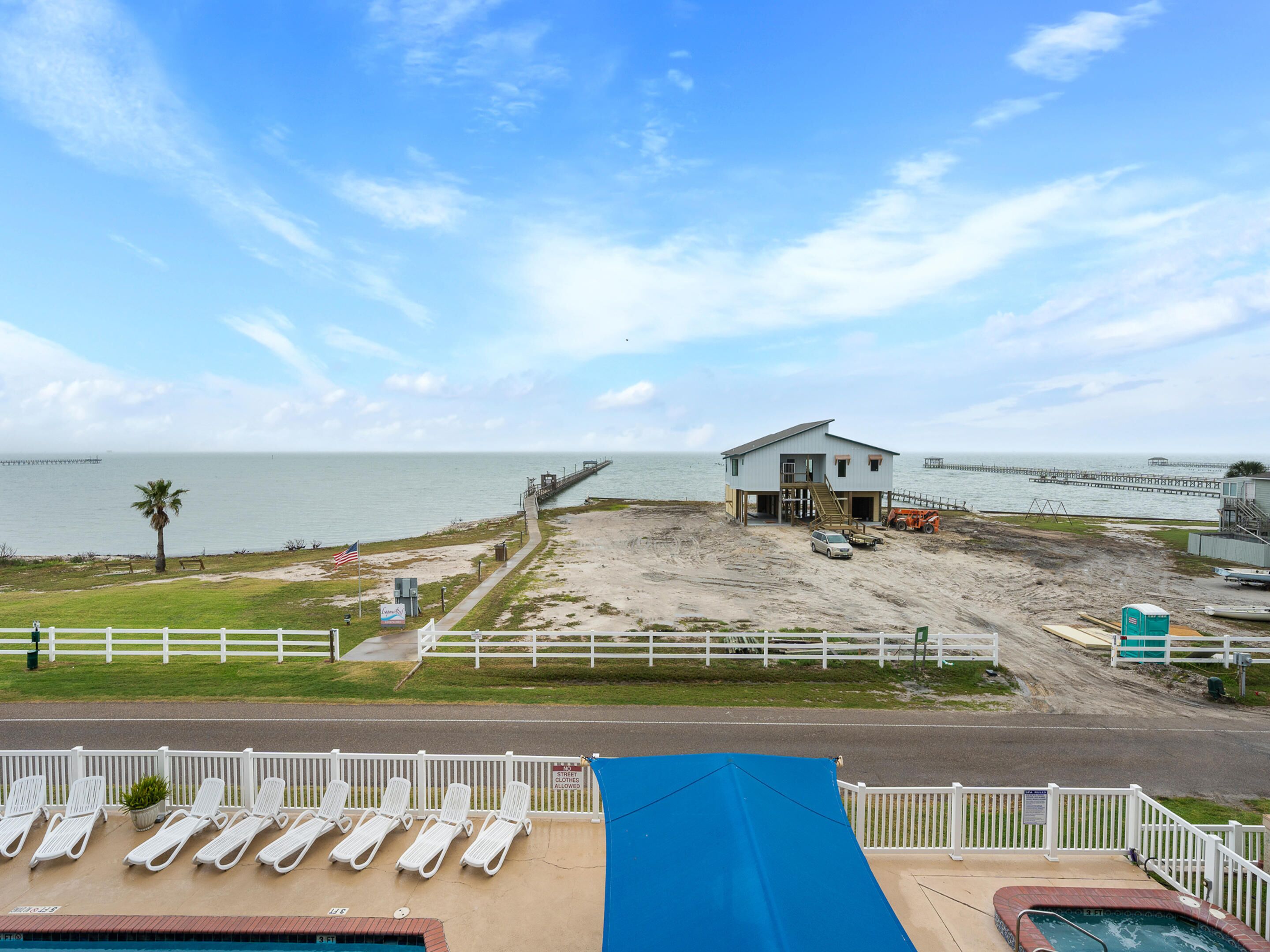 Ett hotell vid stranden med en pool, solstolar och utsikt över havet.
