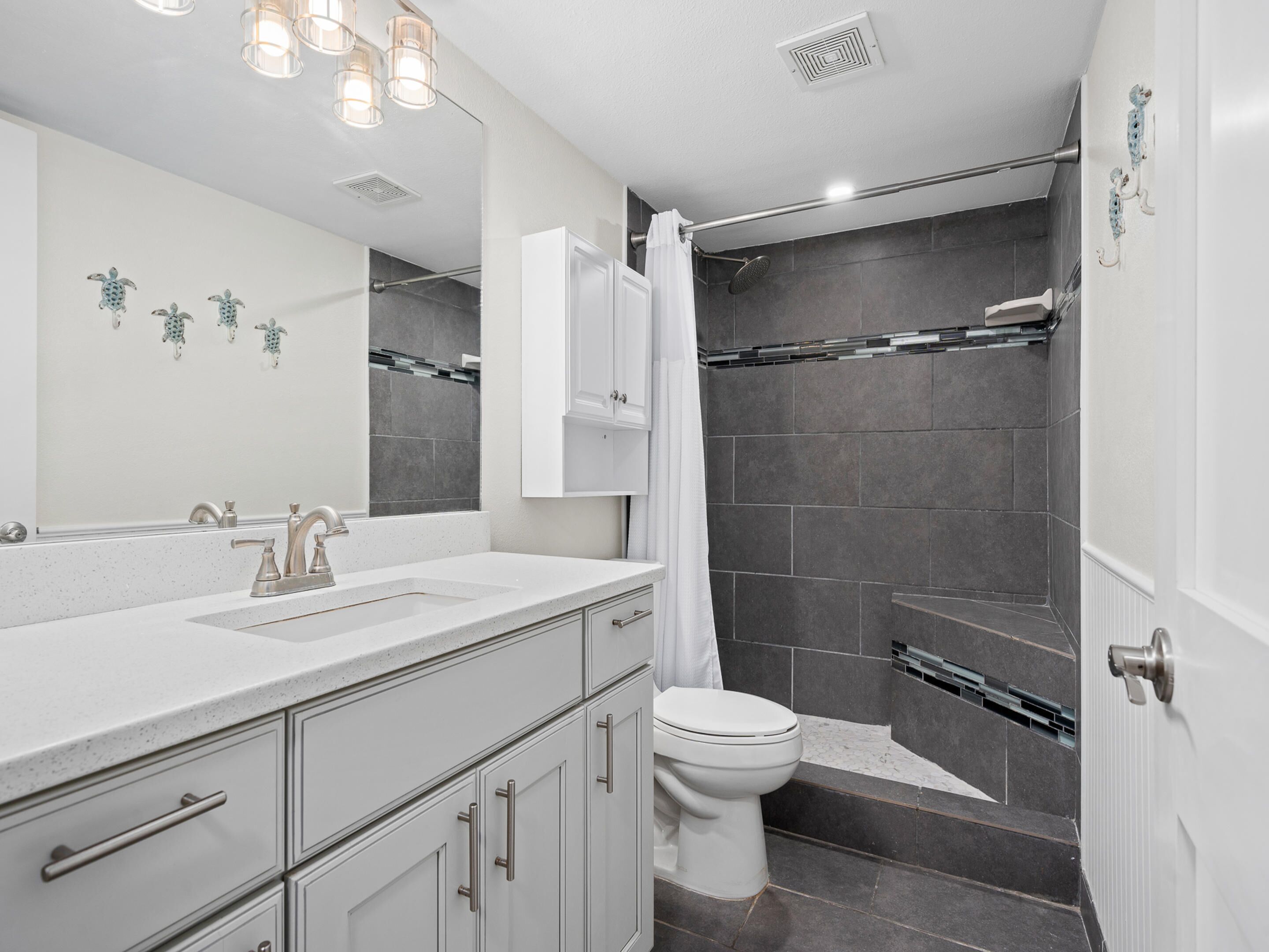 A modern bathroom with a white vanity, a shower with a glass door, and a toilet.