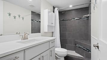 A modern bathroom with a white vanity, a shower with a glass door, and a toilet.