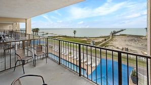 A balcony with a view of the beach, a pool, and a pier. - Laguna Reef 2 by Miss Kitty’s (Rockport)