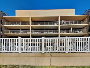 A multi-story building with balconies, a white fence, and a clear blue sky. - Laguna Reef 2 by Miss Kitty’s (Rockport)