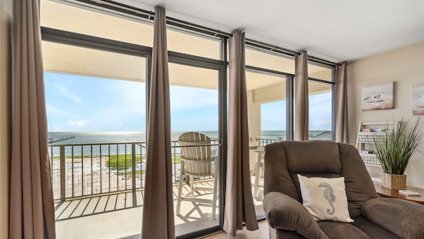 A balcony with a view of the beach, a chair, and a sofa with a cushion. - Laguna Reef 2 by Miss Kitty’s (Rockport)