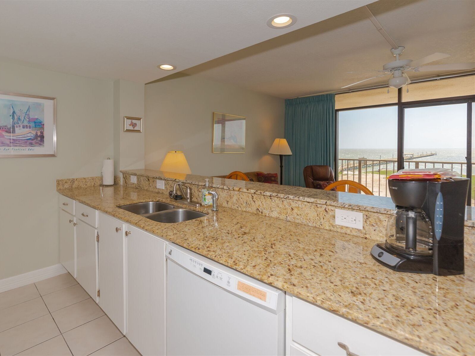 A modern kitchen with granite countertops, a dishwasher, and a coffee maker.