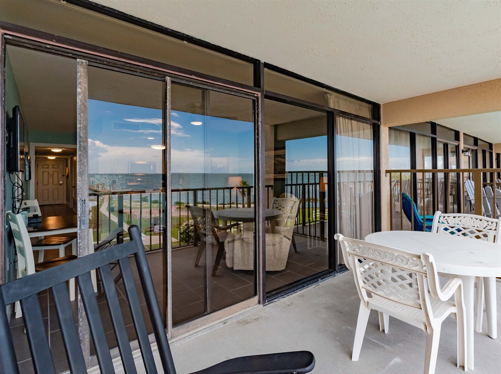 A balcony with a table and chairs, a view of the ocean, and a door leading to an interior space.
