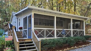 Une cabane dotée d’un porche, d’un escalier en bois et d’une allée gravillonnée.
