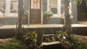 Una casa con porche, puerta de madera y plantas en macetas.