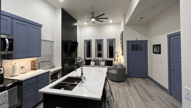 Una cocina moderna con una isla central, electrodomésticos integrados y una zona de comedor con un sofá gris.