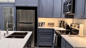 Una cocina moderna con armarios grises, un refrigerador de acero inoxidable, un microondas y un tostador.