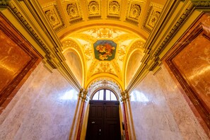 Un intérieur somptueux, avec un plafond haut, des fresques détaillées et une grande porte en arc de cercle.