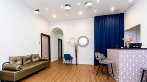 A modern living room with a sofa, chairs, a coffee bar, and a decorative mirror. - Adagio Downtown Rooms (Budapest)