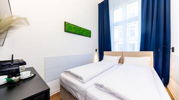 A hotel room with a bed, a coffee machine, and a wall-mounted green plant.