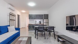 Un soggiorno moderno con un divano blu, un tavolino da caffè e una TV a parete.