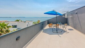 Un balcone con un ombrellone blu, mobili da esterno e vista sul mare.