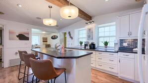 A modern kitchen with a central island, white cabinetry, and pendant lighting.