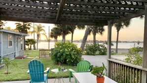 A covered patio with two chairs, a table, and a potted plant. - Little Bay Club by Miss Kitty’s (Rockport)