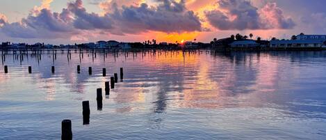 Una riva tranquilla con palafitte nell'acqua e un tramonto sullo sfondo.