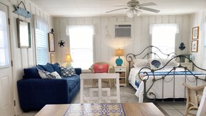 A bedroom with a bed, a sofa, a table, and a chair. - Little Bay Club by Miss Kitty’s (Rockport)