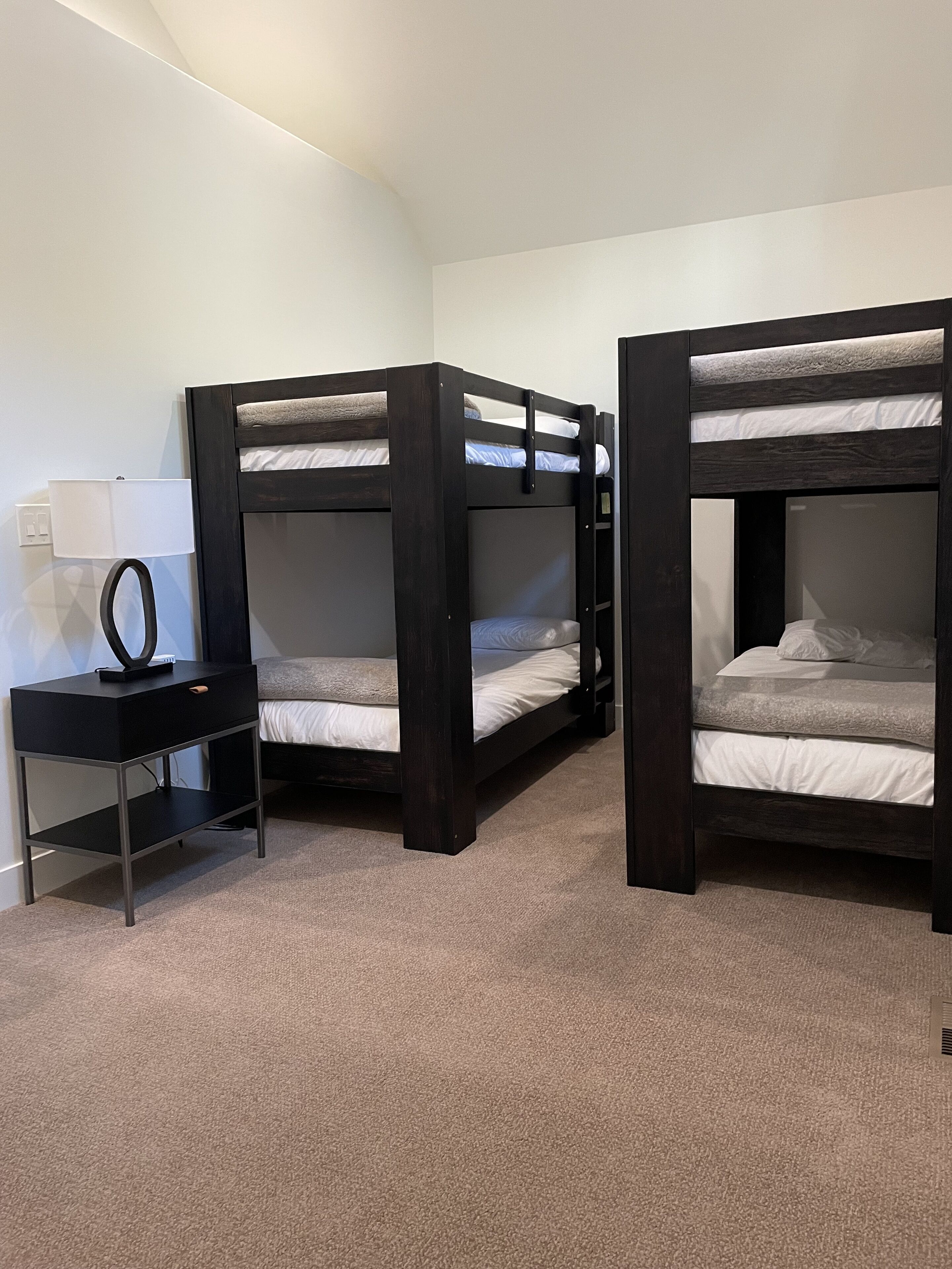 A room with three bunk beds, a small desk with a lamp, and a power outlet.
