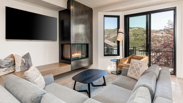 Una sala de estar moderna con chimenea, un televisor grande y vistas al exterior.
