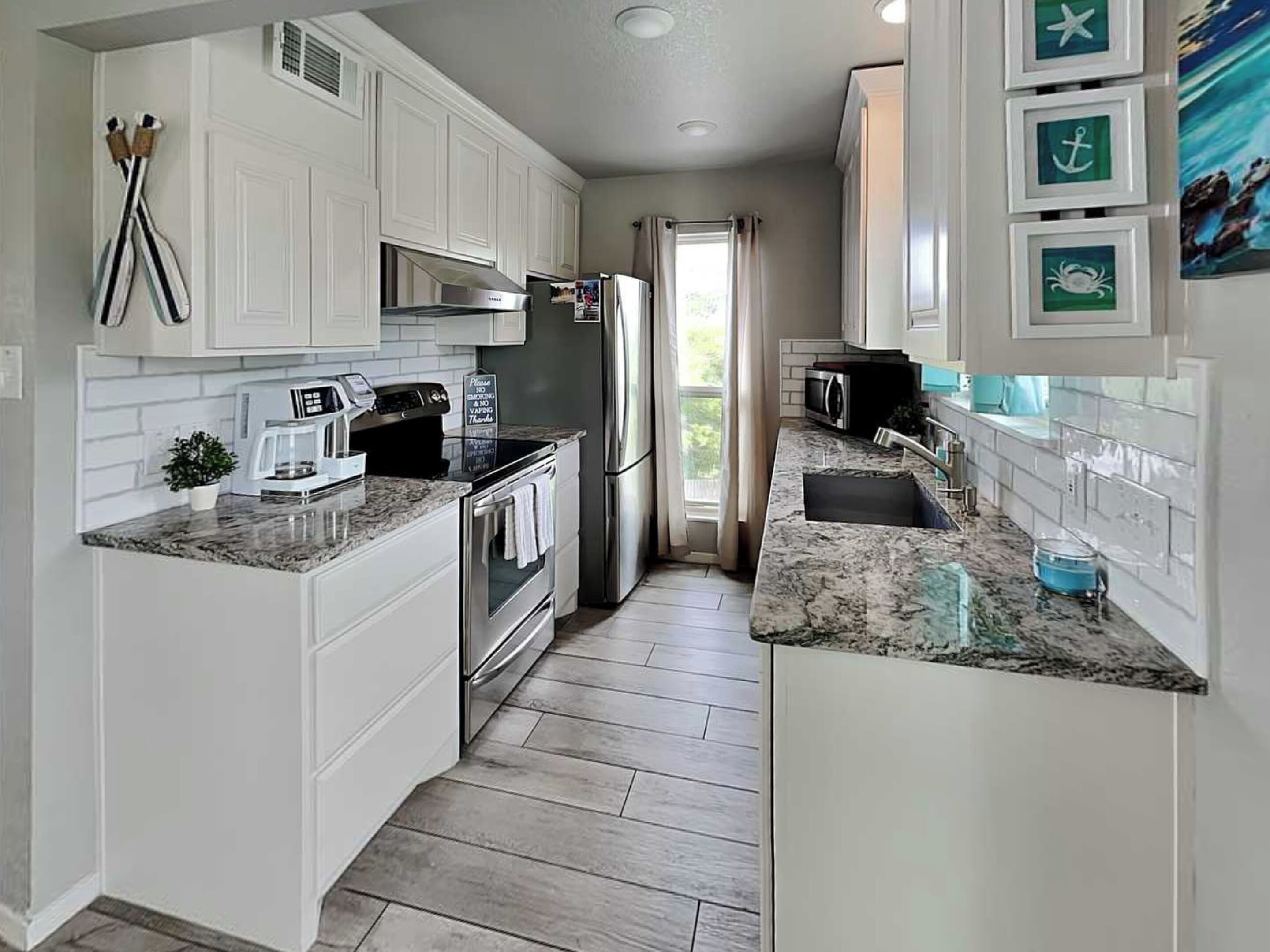 A modern kitchen with white cabinetry, stainless steel appliances, and a granite countertop.