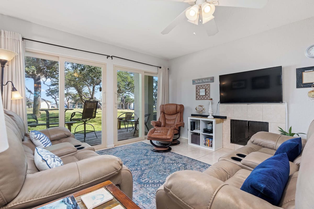 A living room with a sofa, a recliner, a fireplace, and a television.